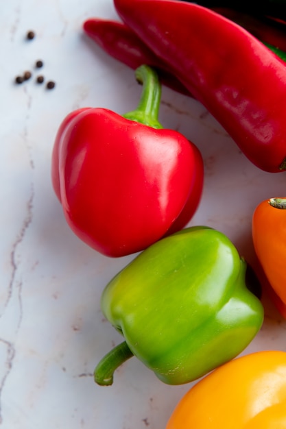 Foto gratuita pimientos rojos y verdes en mesa blanca