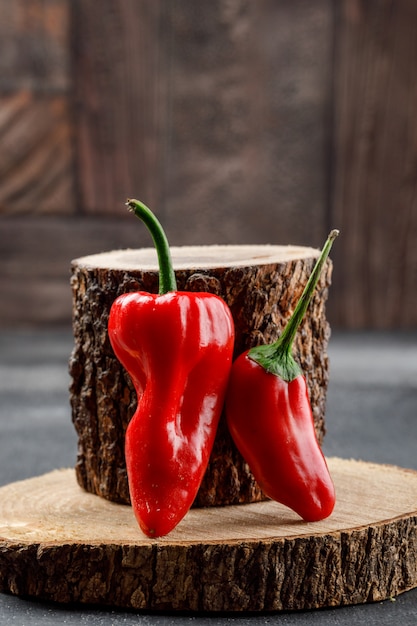 Pimientos rojos con vista lateral de piezas de madera en pared de azulejos grises y piedra