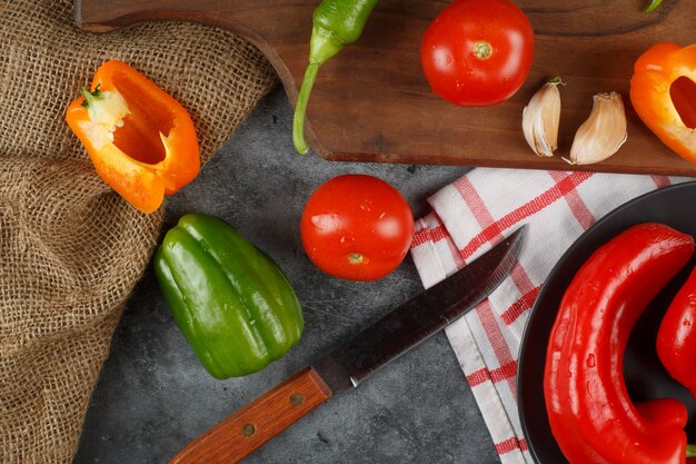 Pimientos, tomates y ajos con un cuchillo alrededor. Vista superior.