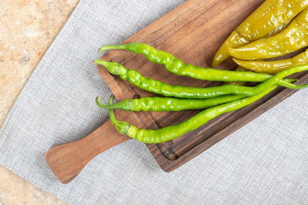 Pimientos verdes en escabeche y frescos sobre tabla de madera.