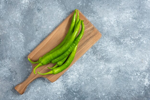 Pimientos verdes sobre tabla de madera.