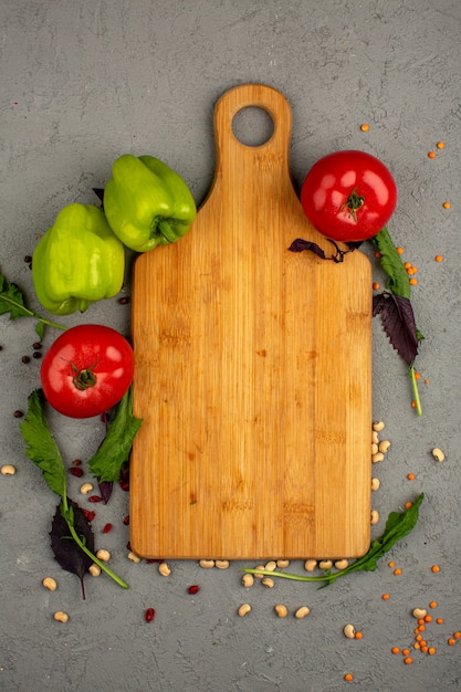 Pimientos una vista superior de tomates verdes maduros y rojos frescos con verdes en un escritorio gris