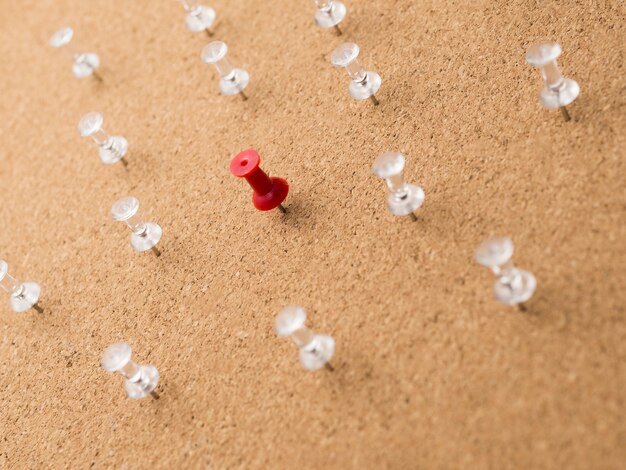 Pin rojo de ángulo bajo rodeado de pines blancos sobre tabla de madera