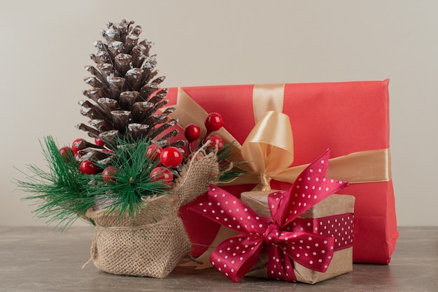 Piña decorada con bayas de acebo y bolsas de regalo en mesa de mármol