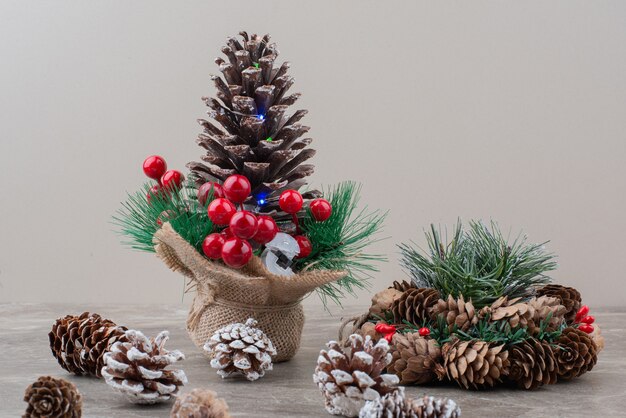 Piña decorada con bayas de acebo y ramas sobre mesa de mármol.