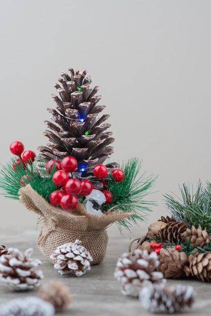 Piña decorada con bayas de acebo y ramas sobre mesa de mármol.