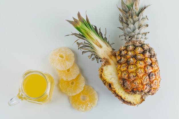 Piña con jugo y aros confitados en superficie blanca