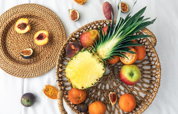 Piña y otras frutas exóticas en una cesta en una vista superior de fondo blanco