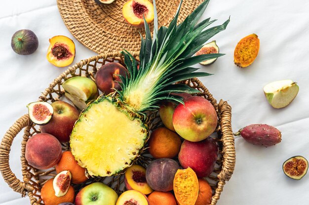 Piña y otras frutas exóticas en una cesta en una vista superior de fondo blanco