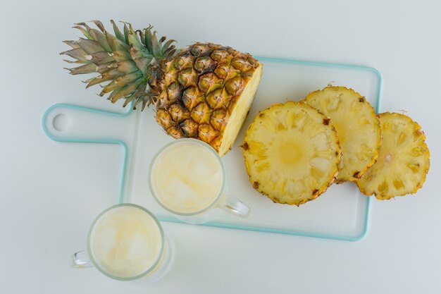 Piña en rodajas con jugo en blanco y superficie de la tabla de cortar