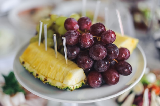 Piña y uva servidas en plato blanco.