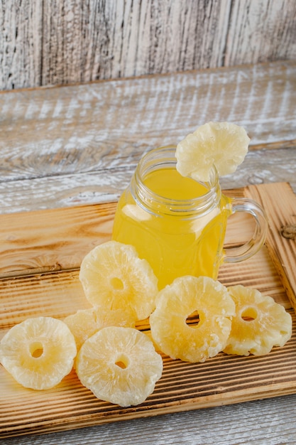 Piñas secas en una bandeja con jugo sobre una superficie de madera