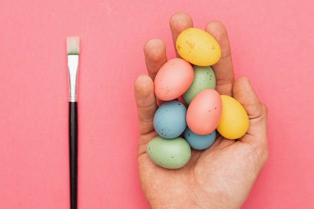 Foto gratuita pincel al lado de la mano con huevos de colores