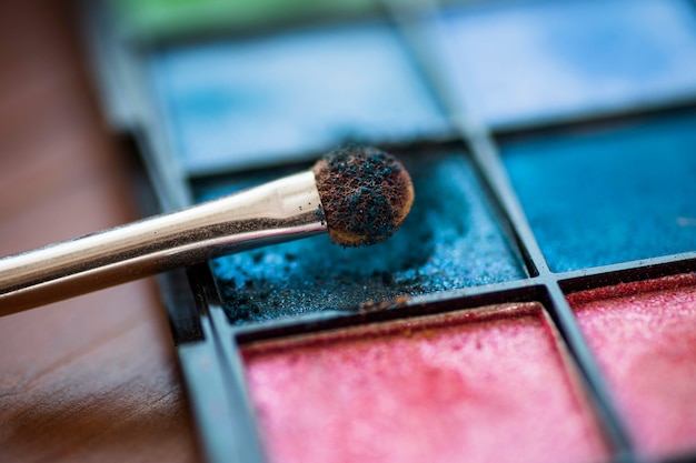 Pincel de maquillaje y paleta de sombras de ojos de colores