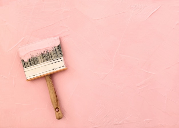 Pincel sobre fondo rosa con textura recién pintada