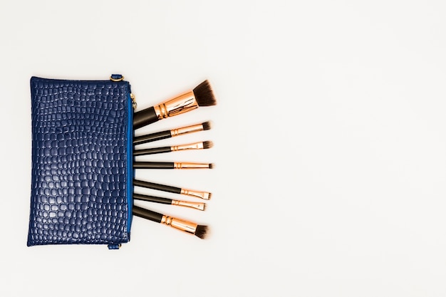 Foto gratuita pinceles de maquillaje en la bolsa azul sobre fondo blanco