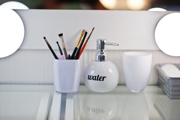 Pinceles de maquillaje con botella de agua en el salón de belleza