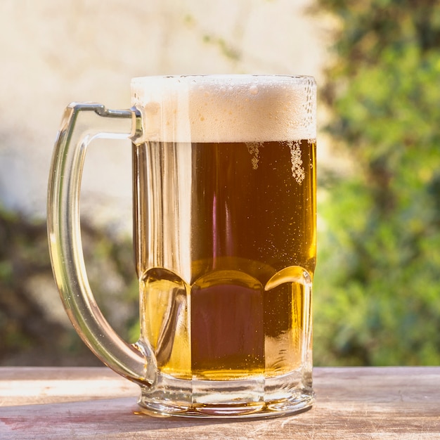 Pinta de ángulo bajo con espuma de cerveza en la mesa