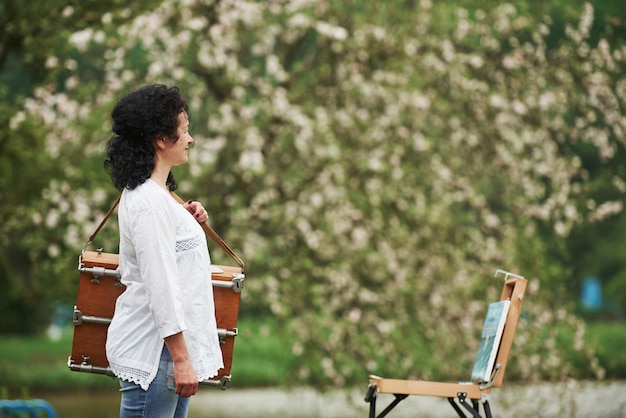 Pintor maduro con estuche de instrumentos pasear por el hermoso parque de la primavera