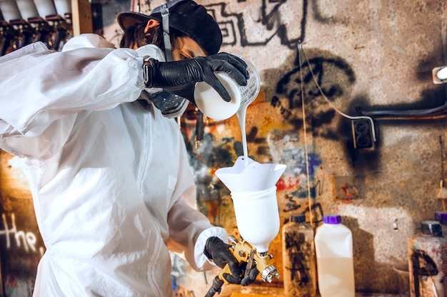 Pintor maestro en una fábrica - pintura industrial de madera con pistola.