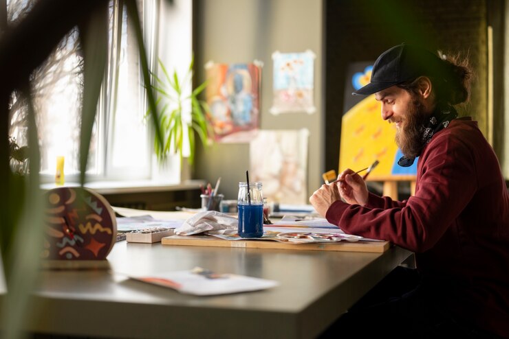 Foto gratuito pintor masculino en el estudio usando acuarela en su arte.