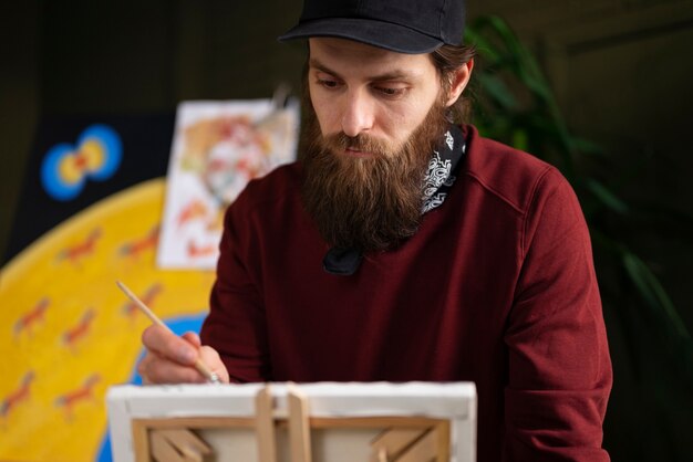 Pintor masculino en el estudio usando acuarela en su arte.