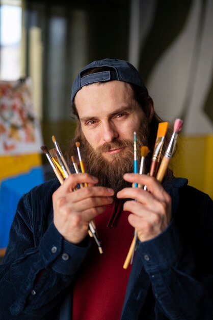 Pintor masculino en el estudio usando acuarela en su arte.