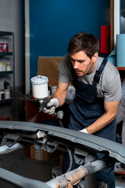 Pintor masculino en overoles haciendo su trabajo en la tienda de autos