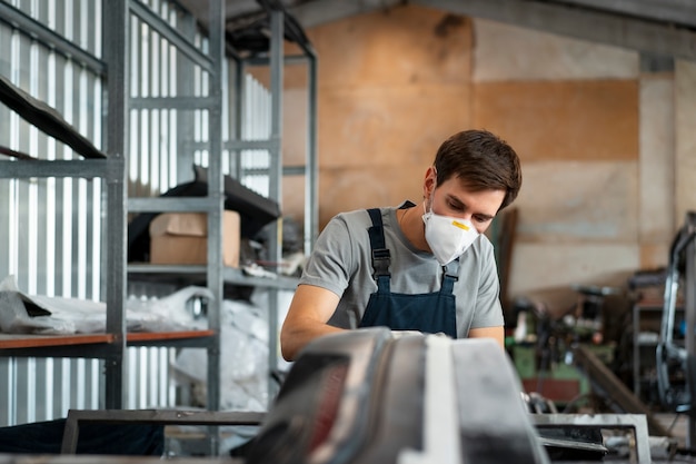 Foto gratuita pintor masculino en overoles haciendo su trabajo en la tienda de autos