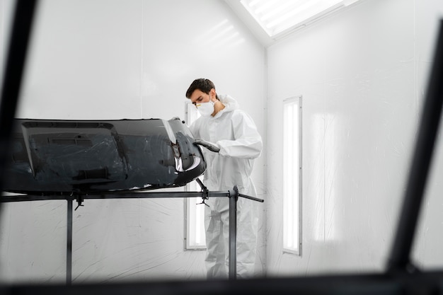 Pintor masculino en traje de materiales peligrosos dentro de la tienda de automóviles