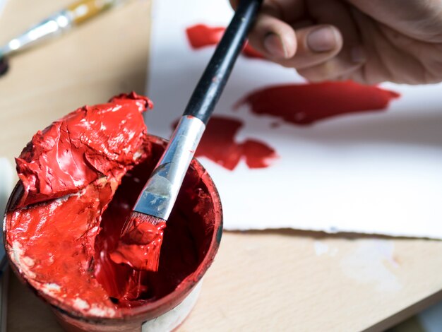 Pintor tomando pintura roja con su pincel.