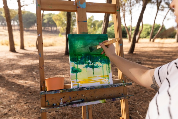 Pintora al aire libre haciendo paisaje sobre lienzo