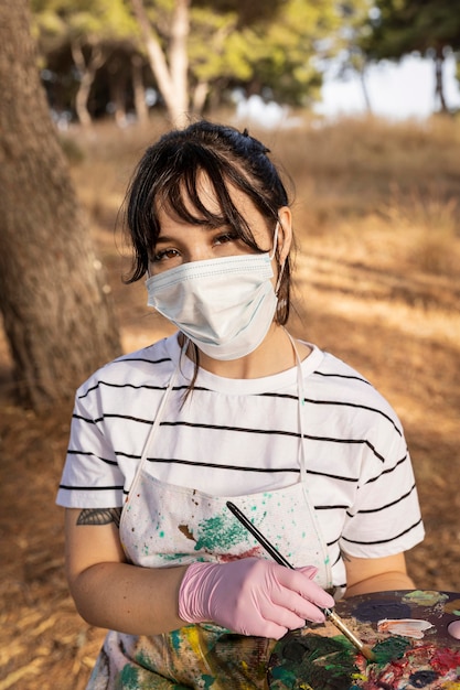 Foto gratuita pintora al aire libre con máscara médica