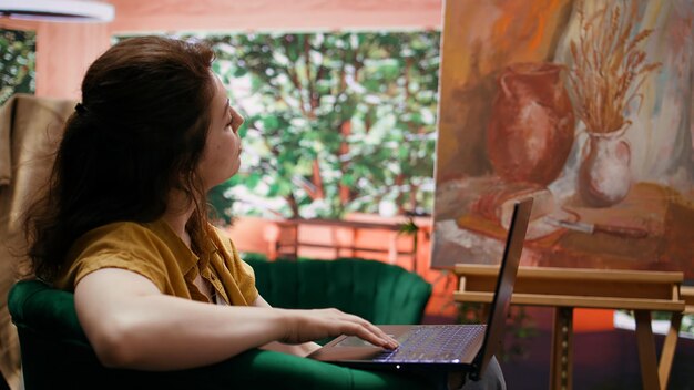 Pintora en busca de inspiración artística en línea en su taller de arte y artesanía