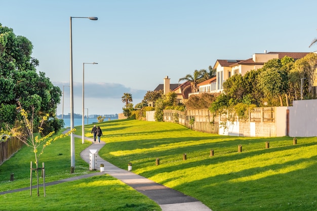 Pintoresco paisaje con hermosas casas a la orilla del mar y un césped bien cuidado con un camino