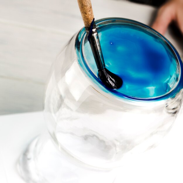 Pintura azul realizada en tarro de cristal con pincel.
