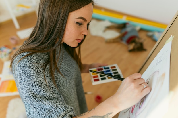 Foto gratuita la pintura femenina de lado y su obra