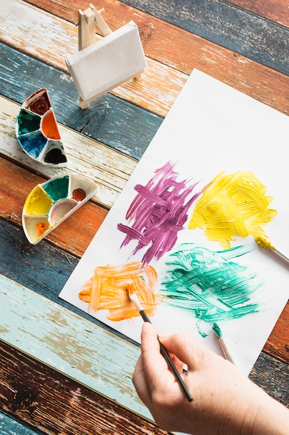 Pintura de la mano de la persona en papel blanco sobre textura de madera