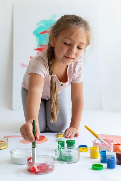 Pintura de niña sonriente de tiro completo con pincel