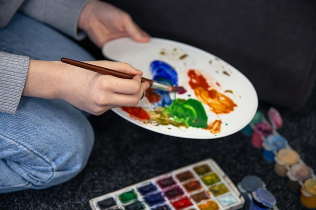 Pintura de primer plano en una paleta en manos femeninas