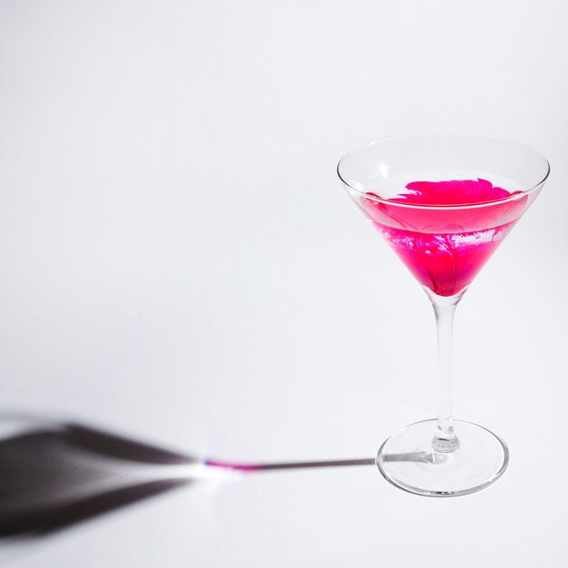 Pintura rosa que se disuelve en el vaso de martini sobre fondo blanco