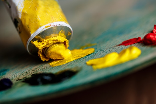 Pinturas al óleo rojas y amarillas en paleta sobre pared de madera