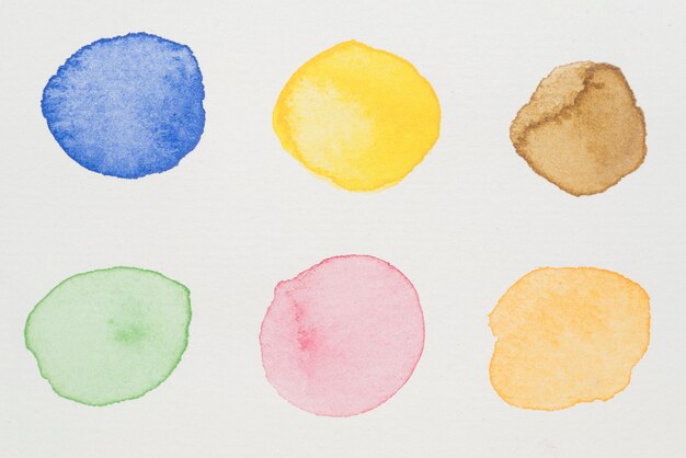 Pinturas en azul, amarillo, marrón, verde, rosa y naranja sobre papel blanco