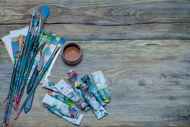 Pinturas y pinceles sobre fondo de mesa de madera