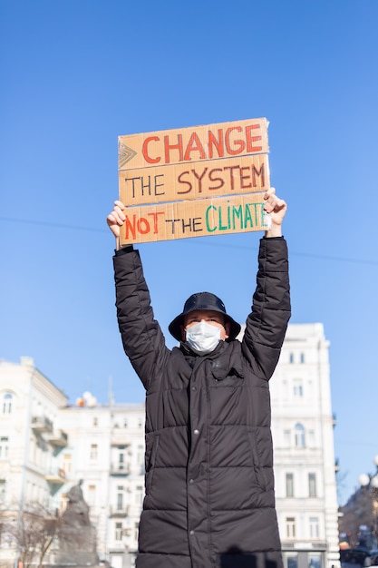 Piquete de protesta en solitario en la plaza de la ciudad salva el concepto del planeta con el lema Cambiar el sistema, no el clima