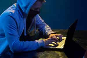 Foto gratuita pirata informático encapuchado que roba información con una computadora portátil
