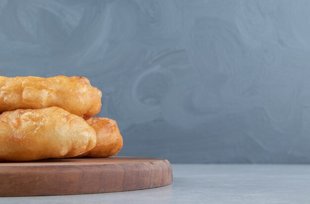 Piroshki al horno con patatas sobre tabla de madera.