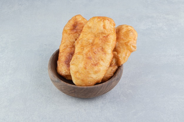 Piroshki al horno con patatas en un tazón de madera.