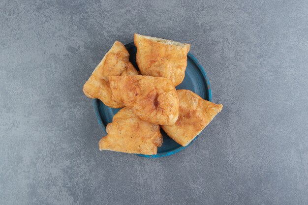 Piroshki en rodajas con patatas en placa azul.