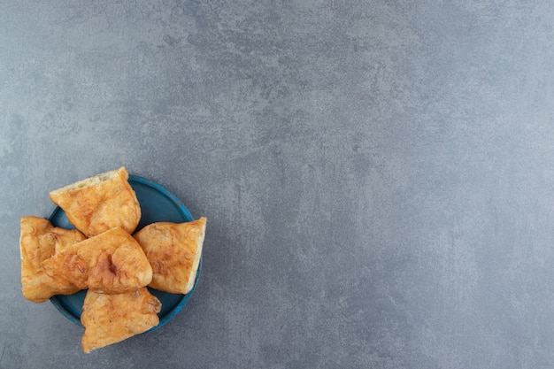 Piroshki en rodajas con patatas en placa azul.